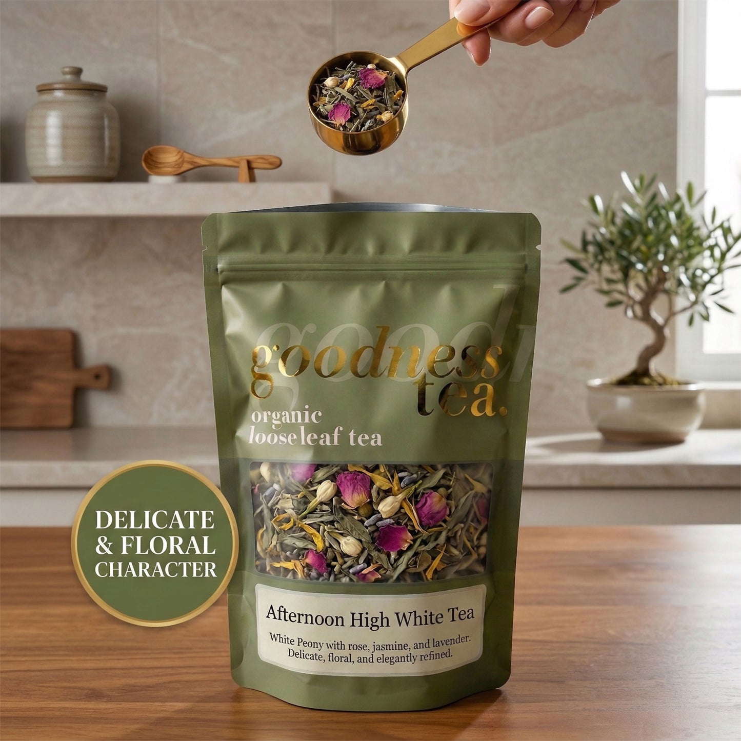Goodness Tea package with a hand holding a scoop of tea leaves in a kitchen setting