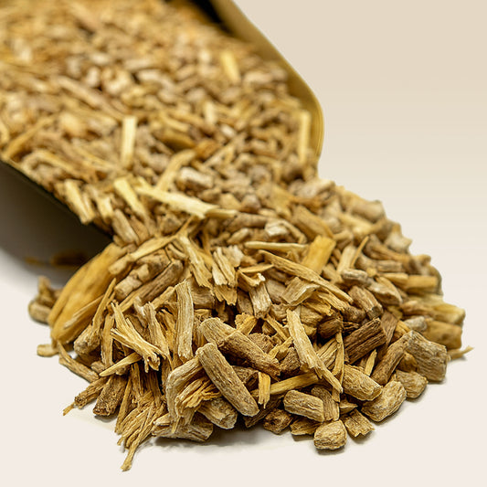 Dried Ashwagandha Root spilling out of a brown paper bag on a light background