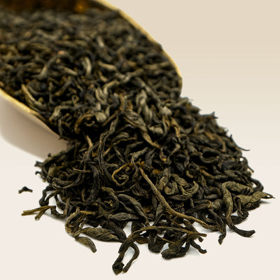 Close-up of dried green Jasmine tea leaves with a white scoop on a light background