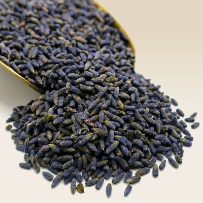 Dried lavender flowers in a gold scoop on a light background
