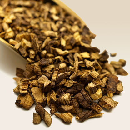 Liquorice Root spilling out of a golden scoop on a white background