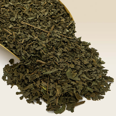 Dry green Peppermint tea leaves in a scoop on a white background