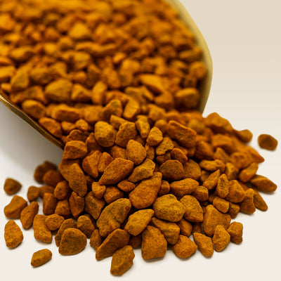 Turmeric chunks spilling out of a scoop on a white background