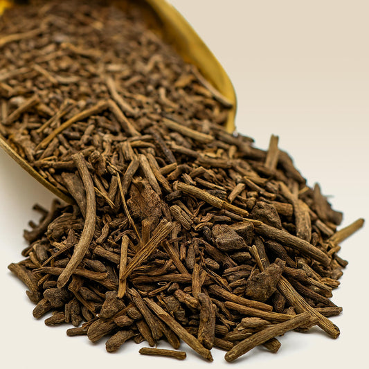 Close-up of Valerian root spilling from a golden scoop onto a white surface.