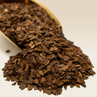 Close-up of a scoop filled with Roasted Yerba Mate on a light background